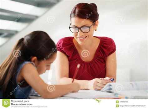 Education With Mom Helping Daughter Doing School Homework At Home Stock