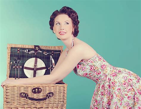 A Woman In A Floral Dress Is Holding A Wicker Basket With A Clock On It