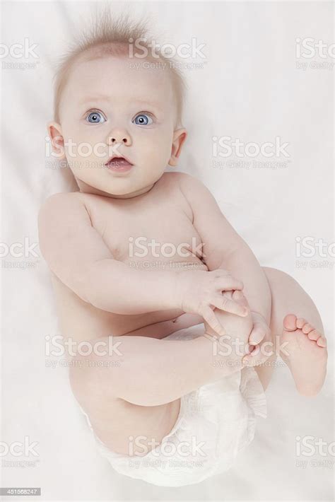 Overhead View Of Baby With Bright Blue Eyes In White Bed Stock Photo
