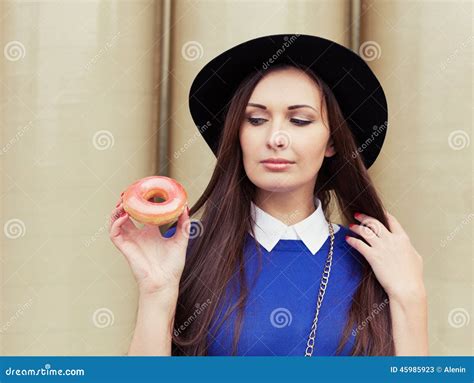 Beautiful Brunette Girl Looking For A Tasty Pink Donut Stock Image