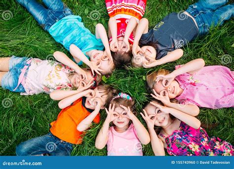 A Group Of Children Lying On The Green Grass In The Park The