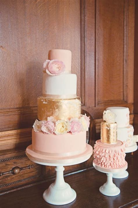 We love the blush, bright pink, and white flowers that complete this white wedding cake. Pink and gold wedding cakes