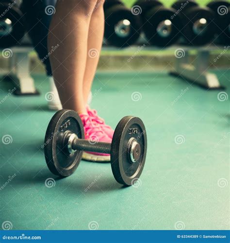 Dumbbell On A Flor In Fitness Gym With Legs In Background Stock Image
