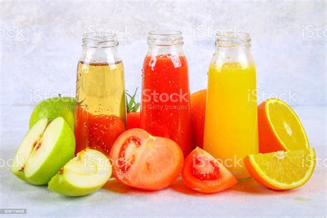 Bottles With Fresh Orange Apple Tomato Juice On A Gray Concrete Table