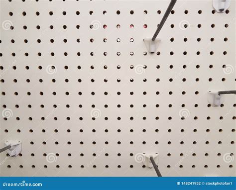 Empty White Pegboard Or Wall With Holes And Metal Hooks Stock Photo