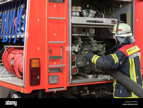 German Firefighter Wearing A Rolled Fire Hose To The Fire Truck Stock