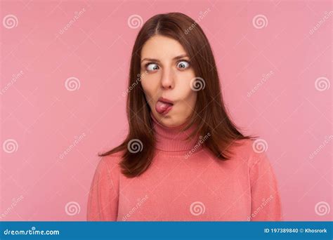 closeup portrait of funny crazy woman crossing eyes and showing tongue having fun making dumb