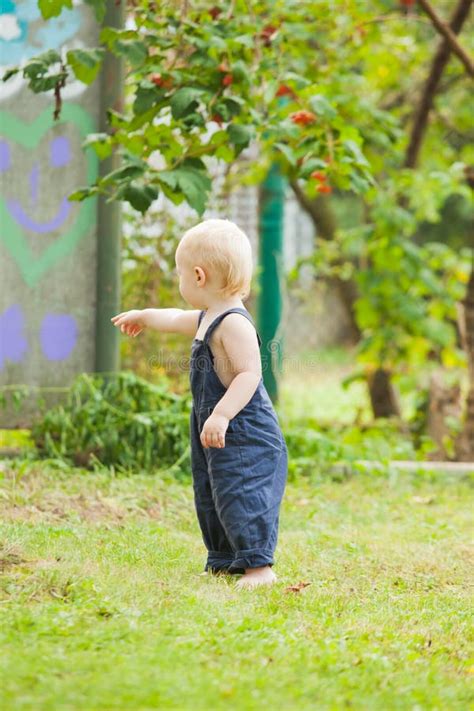 The Cute Baby Boy Enthusiastically Walks In The Summer Garden Stock