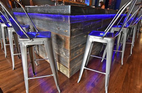A Bar With Stools And Barstools Is Lit Up By Blue Lights At The End