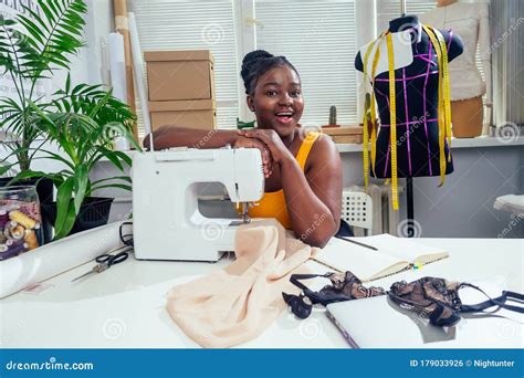 Young African American Dressmaker Woman Sews Clothes On Sewing Machine