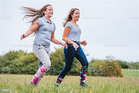 Teen Girls Running Together On Summer Meadow Stock Photo