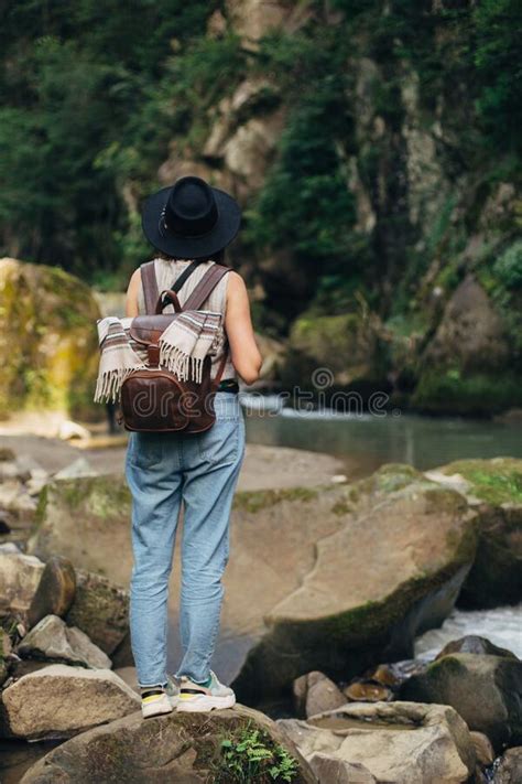 Stylish Woman Traveler With Backpack Relaxing At River In Mountains