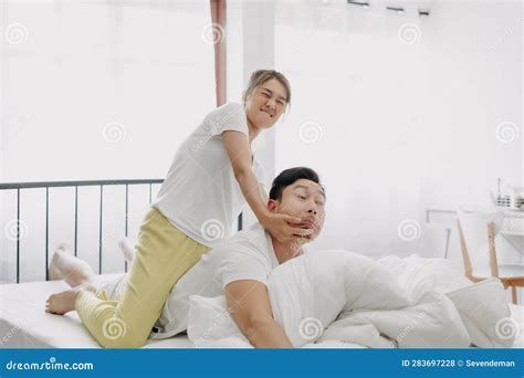 Funny Couple Wife Giving Husband Hurt Massage In White Bedroom Stock