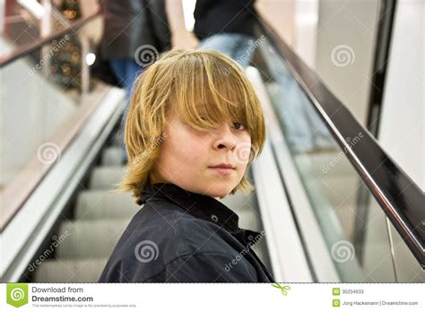 The high voluminous and long blonde hair is parted on the corner of the forehead to look like. Boy With Long Blonde Hair On An Escalator Stock Photos ...