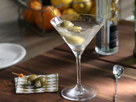 A Martini Glass With Olives In It Sitting On A Table