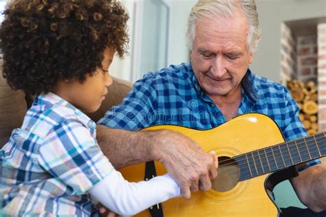 Caucasian Senior Man Teaching Playing Guitar To Biracial Grandson While