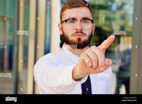 un joven empresario empuja su dedo índice contra una pantalla virtual en el fondo de un edificio