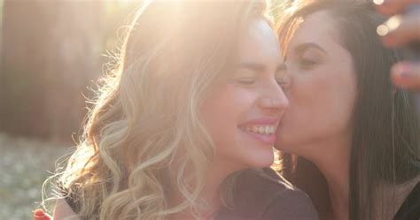Young Woman Kissing Her Lesbian Lover In The Cheek In The Park Stock