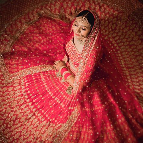 a woman in a red and gold bridal gown is sitting on the floor with her arms crossed
