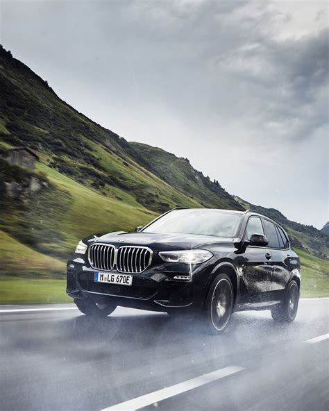 A Black Bmw Suv Driving Down The Road
