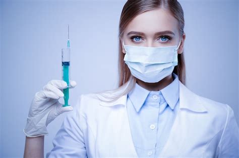 premium photo female doctor in mask and gloves holding syringe on blue