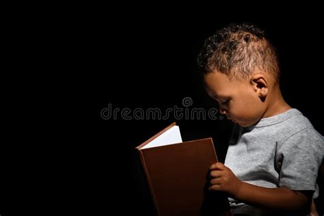 Little African American Boy Reading Book On Dark Background Stock Image