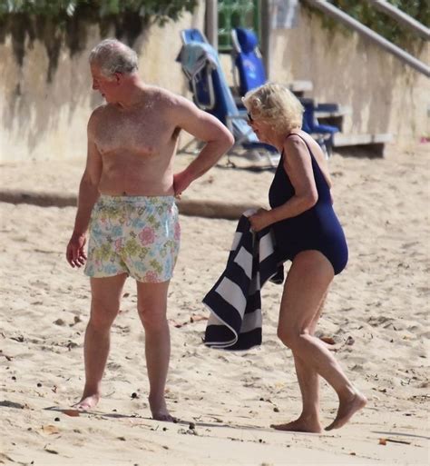 An Older Man And Woman On The Beach With Towels In Their Hands Looking