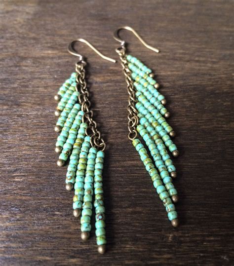 Turquoise And Gold Beaded Earrings On A Wooden Surface With Chain Links