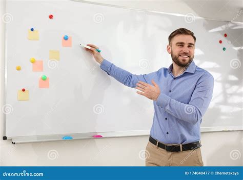 Portrait Of Teacher Writing On Whiteboard In Classroom Stock Image