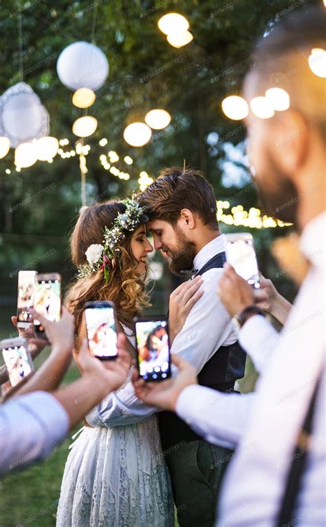 Guests With Smartphones Taking Photo Of Bride And Groom At Wedding
