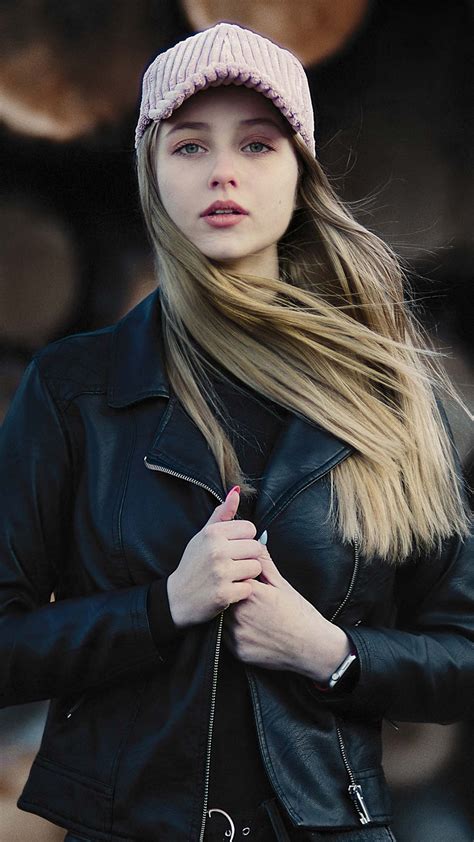 beautiful girl model is standing in blur wood logs background wearing black dress jerkin and