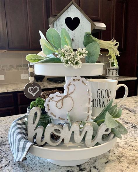 A Three Tiered Tray With Coffee Mugs And Greenery On It Sitting On Top