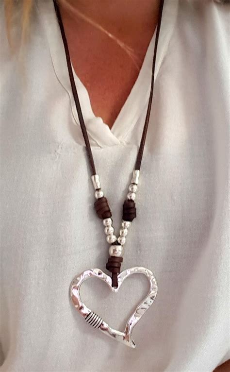 A Woman Wearing A Necklace With A Heart Shaped Pendant
