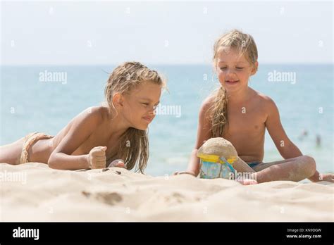 Zwei Kleine Mädchen Spielen Mit Begeisterung In Der Sand Der Am Ufer Des Meeres Stockfotografie