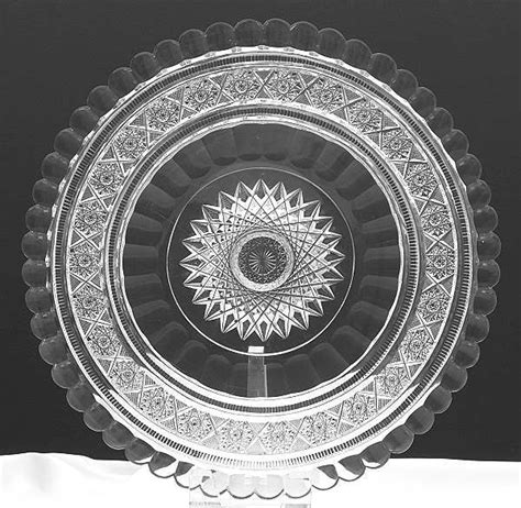 A Glass Plate Sitting On Top Of A White Tablecloth Covered Table With An Intricate Design In The