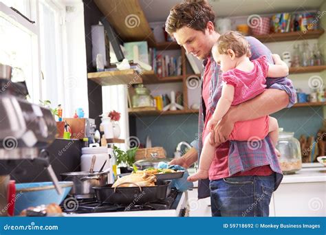 Padre Cooking Meal Whilst Que Detiene A La Hija En Cocina Foto De