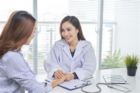 Female Doctor Talks To Female Patient In Hospital Office While W Stock