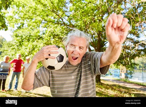 Senior Man With Soccer Ball Is Happy As Winner And Cheers With Clenched