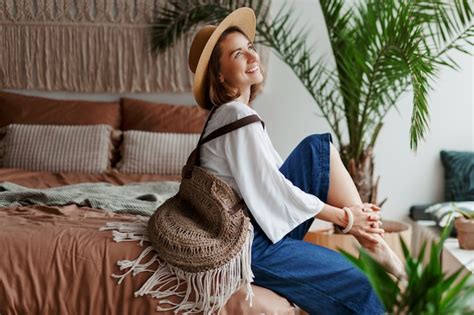 Free Photo Elegant Pretty Woman In Straw Hat And White Blouse Posing At Home Sitting On Bed