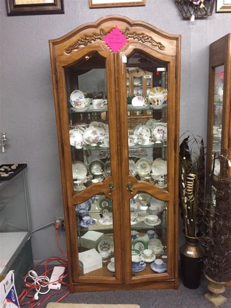 Features adjustable glass shelves, interior lighting, drawer storage and open lower shelf. Vintage Maple Thomasville curio cabinet with ornate top and