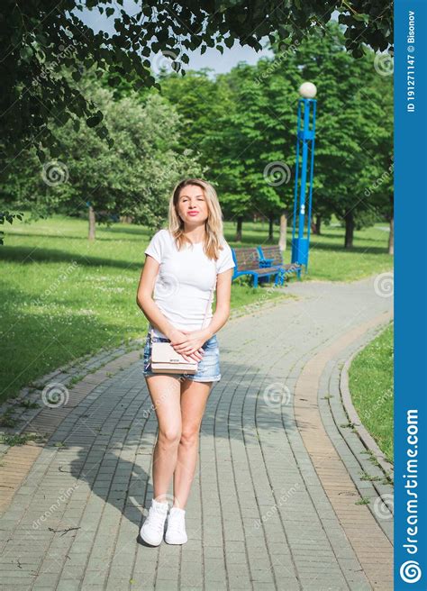 Stylish Young Beautiful Girl In Denim Shorts Walks Along The Footpath