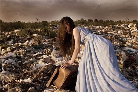The Girl Is Trying To Close The Old Suitcase In The Garbage Dump Stock