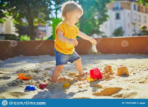 Adorable Little Girl Having Fun On Playground In Sandpit Stock Photo