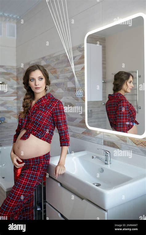 A Pregnant Woman In The Bathroom Female Dressed In Red Pajama And Open Belly Enjoying Her