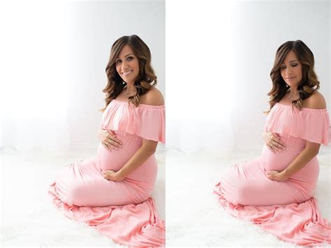A Pregnant Woman In A Pink Dress Sitting On A White Blanket And Smiling
