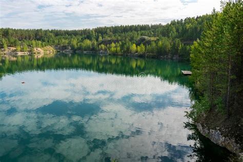 Turquoise Lake In The Middle Of Rocky Shores And Forest With Reflective