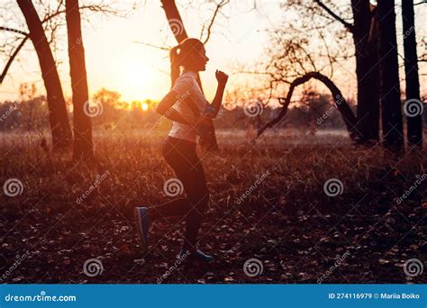 Young Female Runner Training In Autumn Park Woman Working Out With