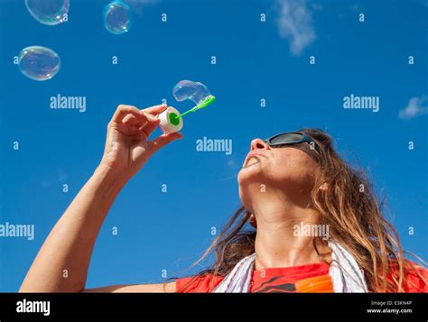 Woman Blowing Bubbles Against Blue Sky Stock Photo Alamy