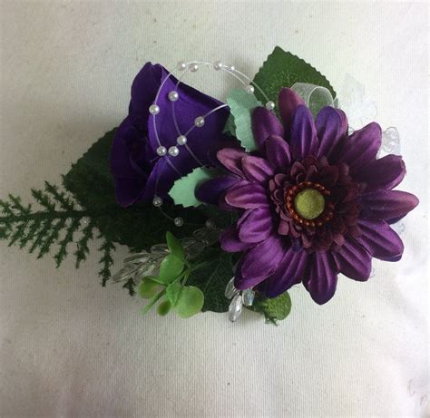 an artificial wedding corsage featuring a purple rose and gerbera with foliage gerbera wedding
