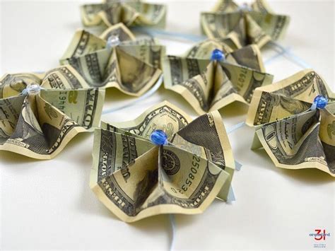 Several Origami Flowers Made Out Of One Hundred Dollar Bills On A White